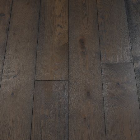 A close-up of dark carbon-coloured wood plank flooring, featuring deep black and charcoal hues. The smooth, matte finish emphasizes the sleek, modern appearance, while subtle grain patterns add a hint of texture.